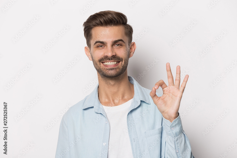 Guy with white toothy smile showing ok sign studio shot