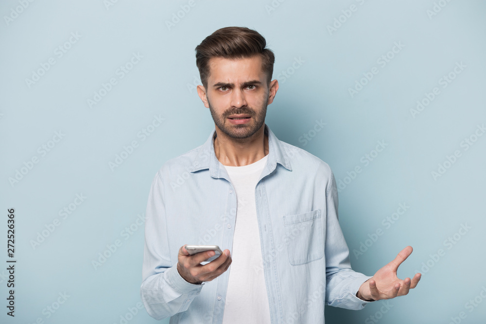 Angry man holding smart phone looking at camera studio shot Angry man holding smart phone looking at camera studio shot