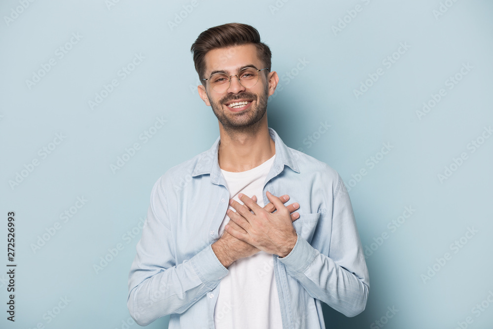 Grateful guy in glasses put hands on chest studio shot Grateful guy in glasses put hands on chest studio shot