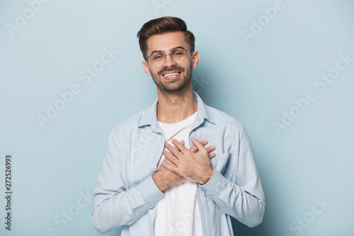 Grateful guy in glasses put hands on chest studio shot