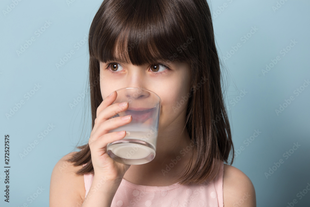 Closeup portrait little girl drinking milk studio shot on blue Closeup portrait little girl drinking milk studio shot on blue