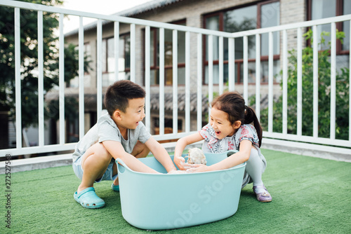 Adorable boy and girl washing pet dog in yard photo