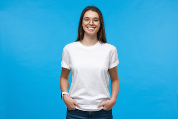 Closeup of positive European female dressed in white top isolated on blue background