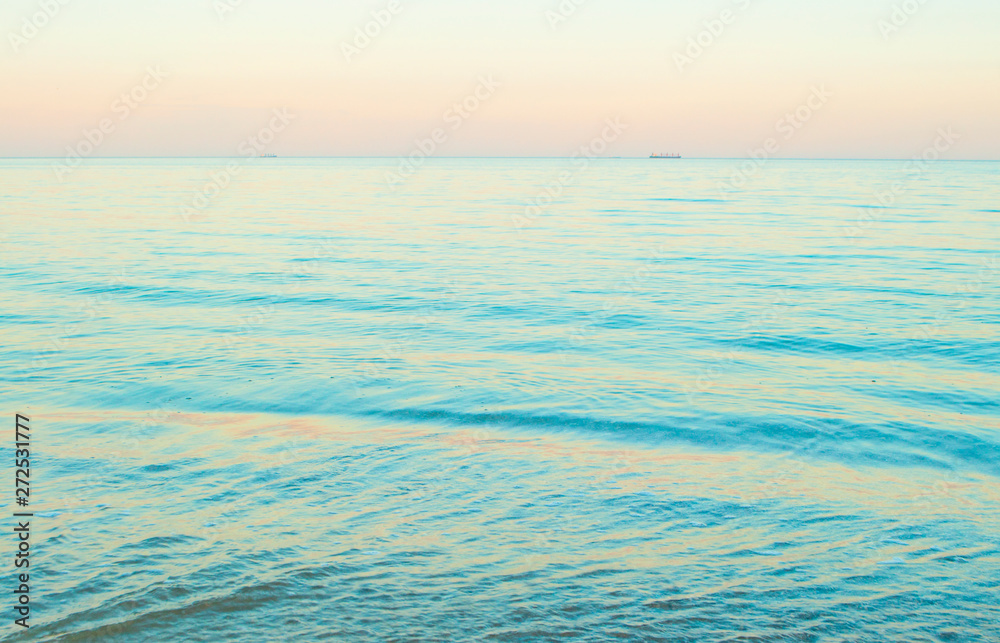 Obraz premium Beautifu blue sea water background. Beautiful pink color sunset on the beach.