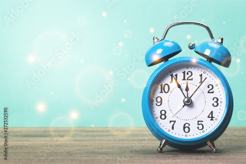 Blue retro alarm clock on wooden table on pastel background