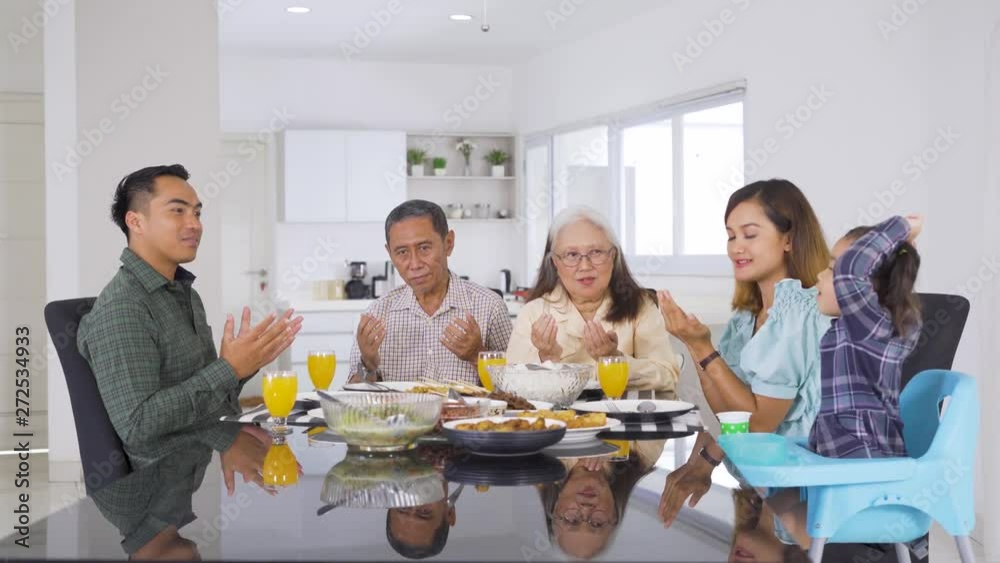 Three generation happy muslim family praying together before eating in dining room at home. Shot in 4k resolution Three generation happy muslim family praying together before eating in dining room at home. Shot in 4k resolution