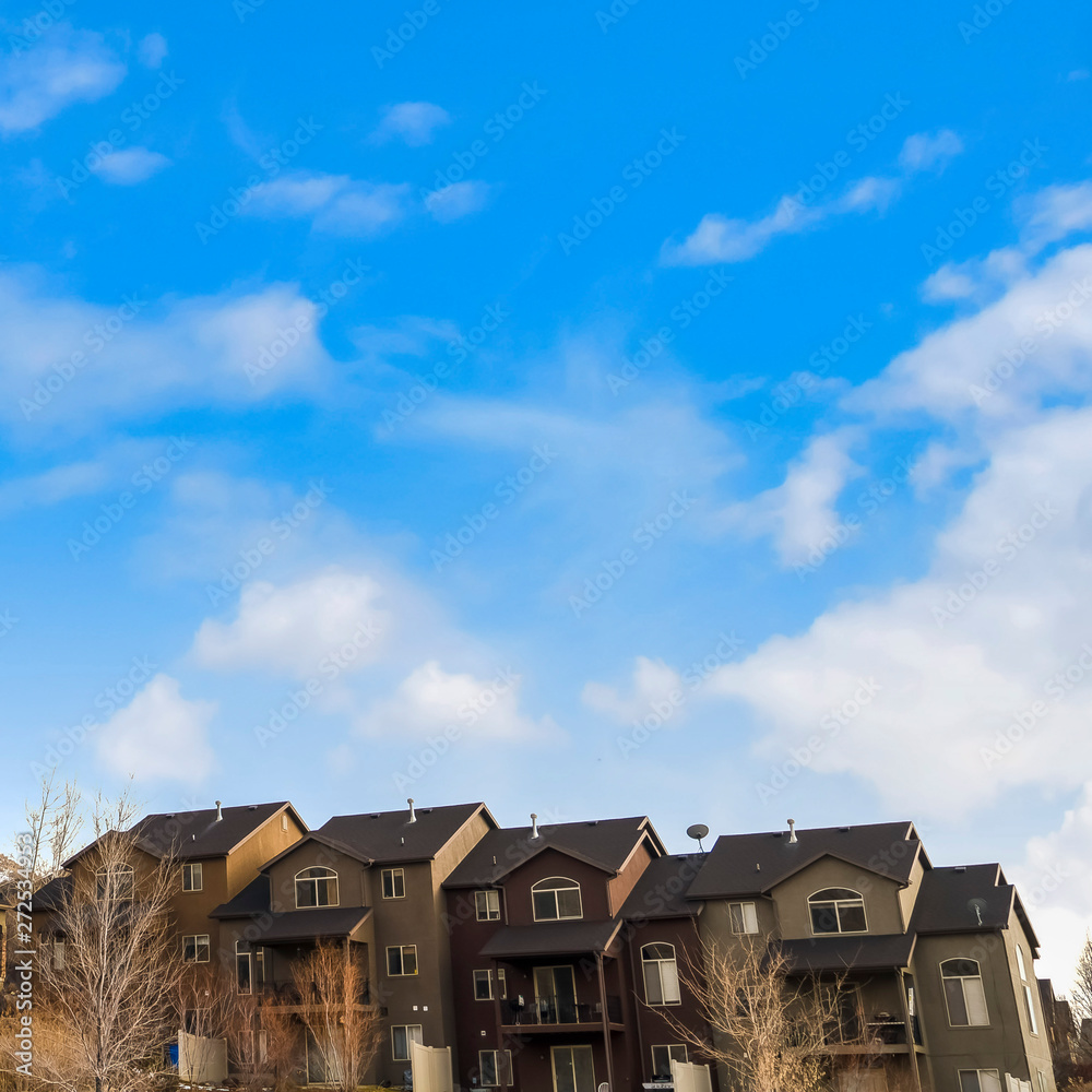 Square frame Row of houses on a mountain slope with cloudy blue sky in the background Square frame Row of houses on a mountain slope with cloudy blue sky in the background