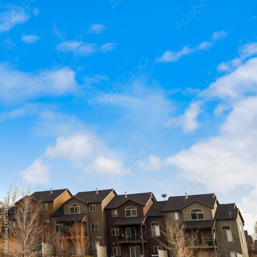 Square frame Row of houses on a mountain slope with cloudy blue sky in the background