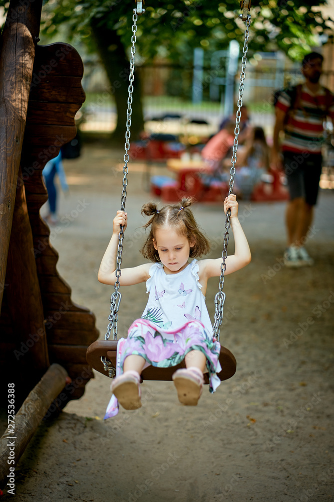Little beautiful sad girl on swing with pensive face on the playground Little beautiful sad girl on swing with pensive face on the playground