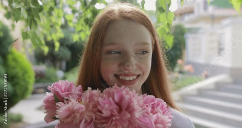 attractive girl with a bouquet of pink peonies in the garden near the country house. in slow motion. Shot on Canon 1DX mark2 4K camera photo