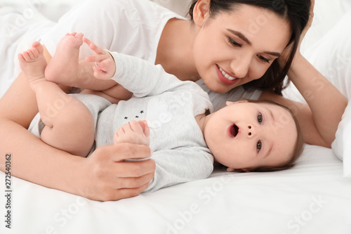 Cute baby and mother lying on bed