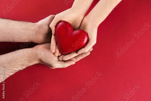 Couple holding decorative heart on color background  top view. Space for text