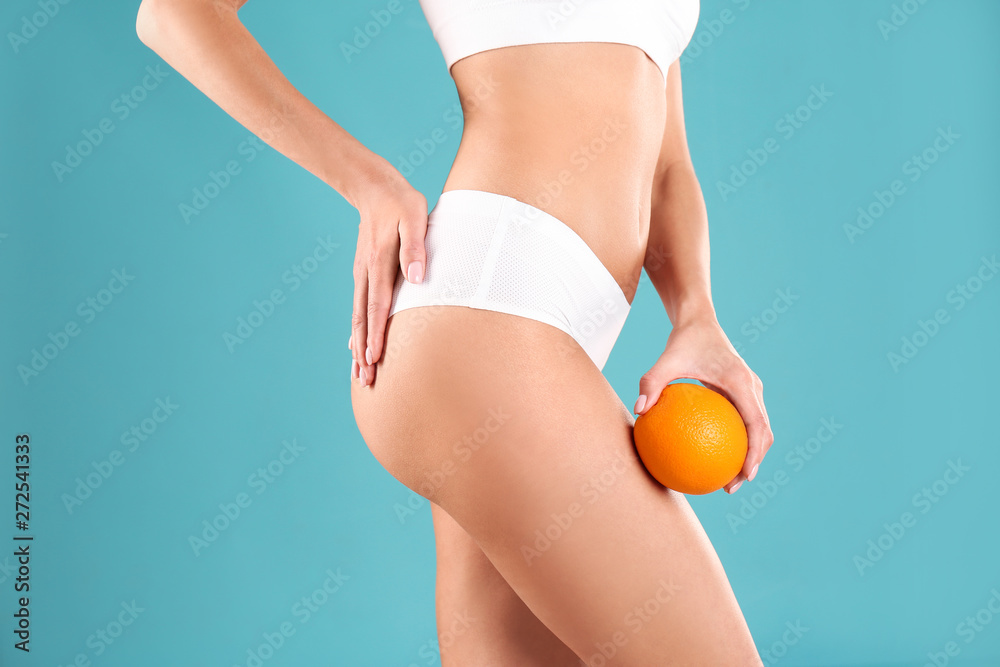 Closeup view of slim woman in underwear with orange on color background.  Cellulite problem concept Stock Photo