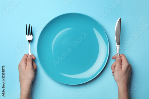 Woman with fork, knife and empty plate on color background, top view © New Africa