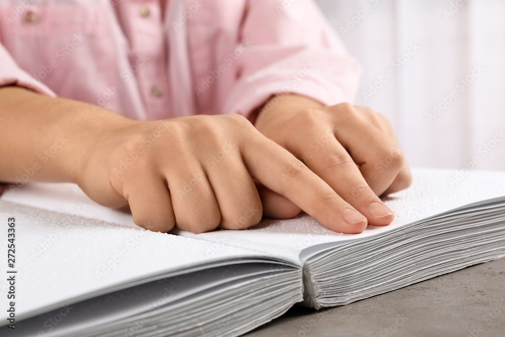 Blind person reading book written in Braille at table, closeup Blind person reading book written in Braille at table, closeup