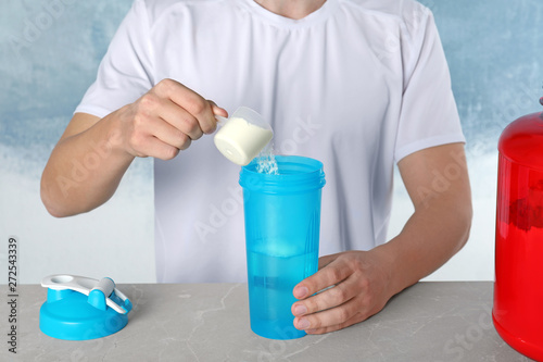 Man preparing protein shake with powder at table, closeup © New Africa