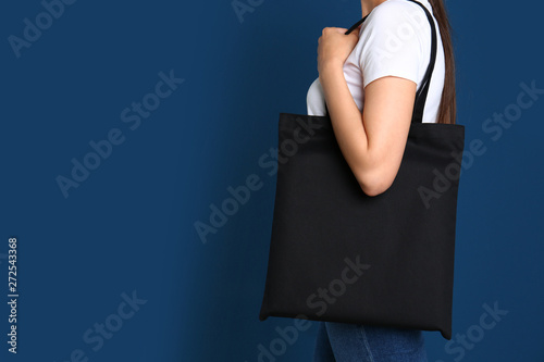 Woman with stylish blank eco bag against color background, closeup. Space for text