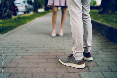 Close up on young man and female legs standing on the pathway pavement waiting date in love