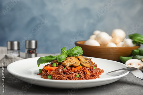 Fototapeta Naklejka Na Ścianę i Meble -  Plate of tasty brown rice with vegetables and mushrooms on grey table