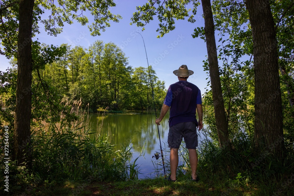 angler standing on the lake shore during summer day angler standing on the lake shore during summer day