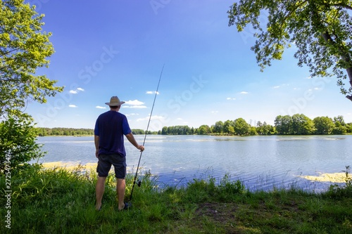 angler standing on the lake shore during summer day