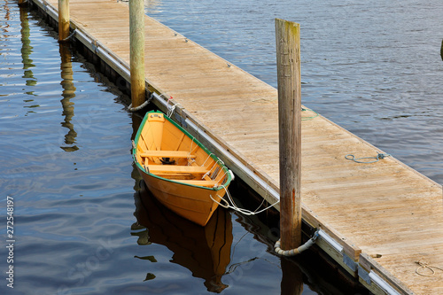 A yellow wooden boat docking at Perkins Cove on a Sunny Day, Ogunquit, Maine.  photo