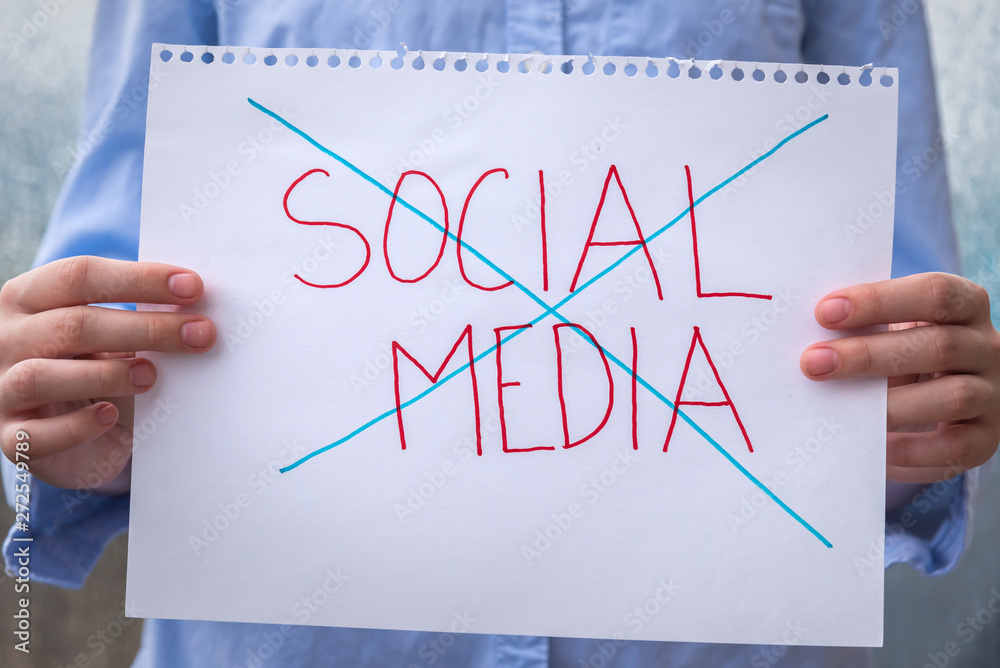 Hands holding sign with words social media crossed out Hands holding sign with words social media crossed out