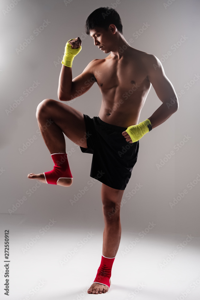 The handsome man wearing yellow mitt and red ankle,raise hand up and fist,raise knee up,show thai boxing pattern The handsome man wearing yellow mitt and red ankle,raise hand up and fist,raise knee up,show thai boxing pattern