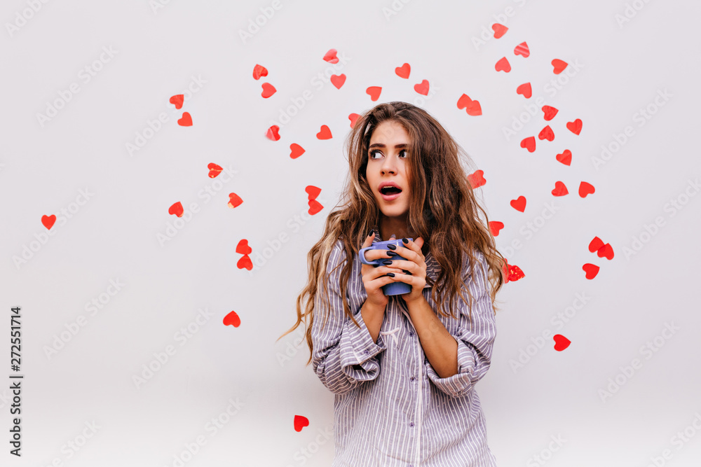 Amazed adorable girl holding blue mug in hands. Studio photo of cute emotional lady in trendy pajamas. Amazed adorable girl holding blue mug in hands. Studio photo of cute emotional lady in trendy pajamas.