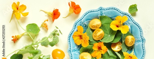 Fototapeta Naklejka Na Ścianę i Meble -  salad with nasturtium leaves and flowers of the plant. bright summer salad with edible yellow flowers and yellow tomatoes with egg. top view.