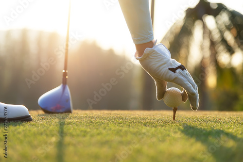 hand of woman golf player gentle put a golf ball onto wooden tee on the tee off, to make ready hit away from tee off to the fairway ahead. Healthy and Lifestyle Concept. photo