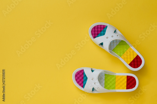 Colorful women's flip-flops on a yellow background. The concept of a holiday by the sea. Flat lay.