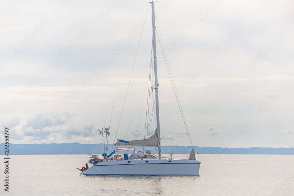 Catamaran sail boat at the coast line anchoring, in a luxury lifestyle summer sunny day photo