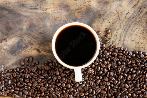 Fresh coffee with fragrant aroma in a white cup and coffee beans on an old wooden table. Top view - image