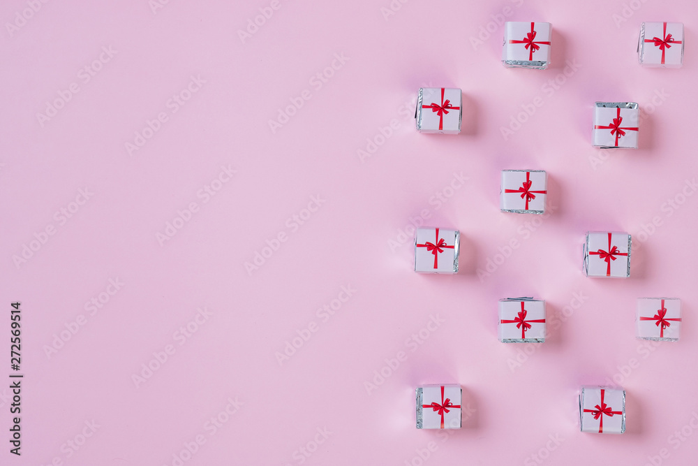 pattern with small christmas gifts wrapped in paper on pink background.Holiday greeting card with copy space.Pattern of gift paper boxes with red ribbon on pastel background.Creativity concept. pattern with small christmas gifts wrapped in paper on pink background.Holiday greeting card with copy space.Pattern of gift paper boxes with red ribbon on pastel background.Creativity concept.