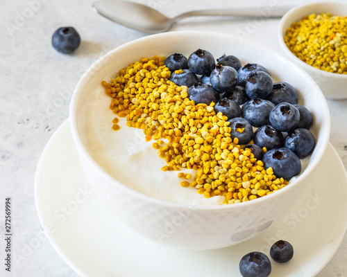 Bowl of greek yogurt, bee pollen and fresh berries on white stone background