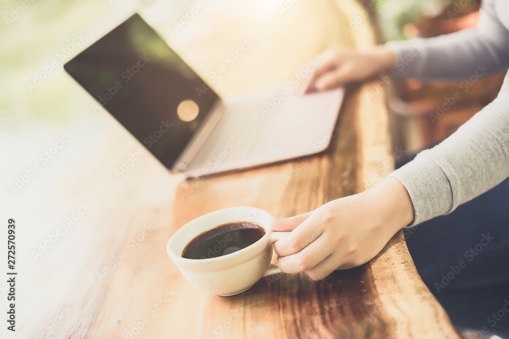 Young woman sitting in coffee shop at wooden table, drinking coffee and using laptop. Young woman sitting in coffee shop at wooden table, drinking coffee and using laptop.
