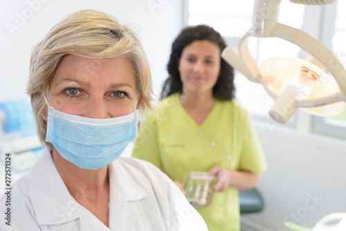 dentist with mask posing with assistant background