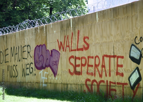 Mit Stacheldraht gesicherte und gesprayte Betonmauer