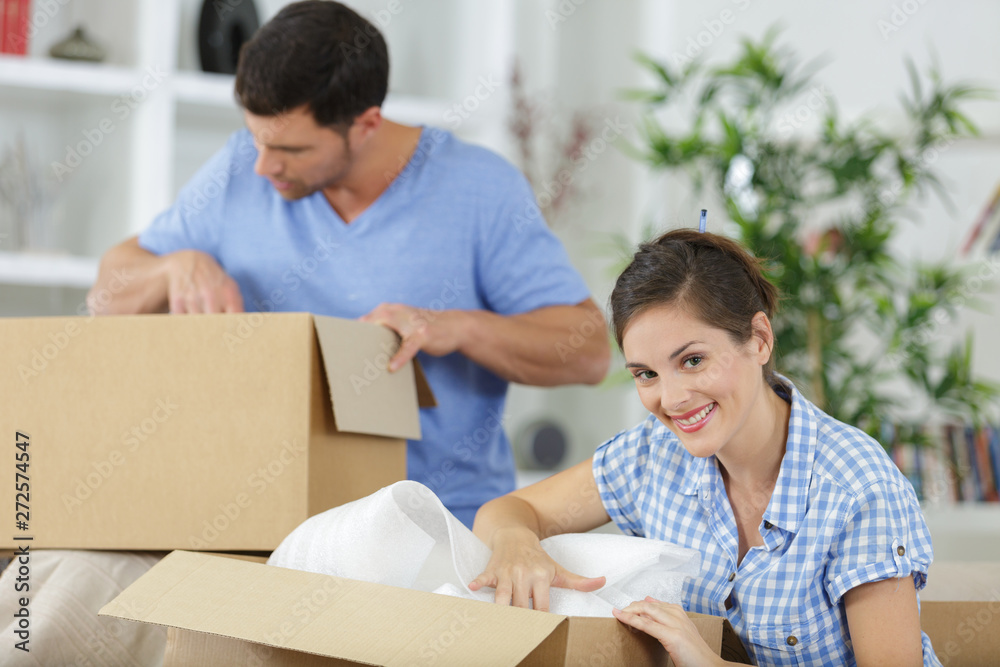 lovely couple unpacking stuff after relocation to new home lovely couple unpacking stuff after relocation to new home