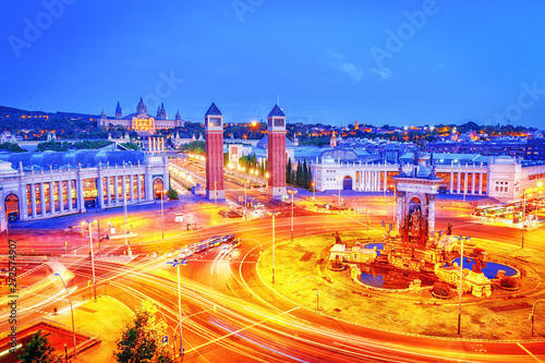 Placa de Espanya - iconic landmark in Barcelona, Spain. Beautiful dusk panoramic view on Square of Spain or Plaza de Espana. Roundabout light trails of cars. Old castle of Barcelona in background.