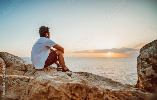 Lonely guy observing the sunset from a cliff in Cyprus