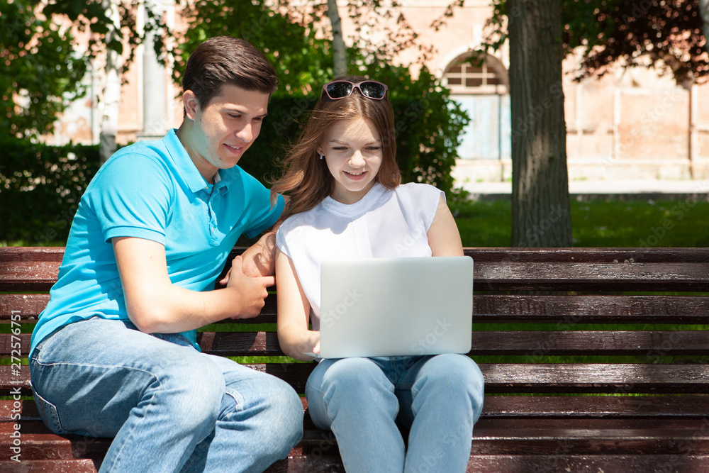 Young handsome couple using notebook in the public park Young handsome couple using notebook in the public park