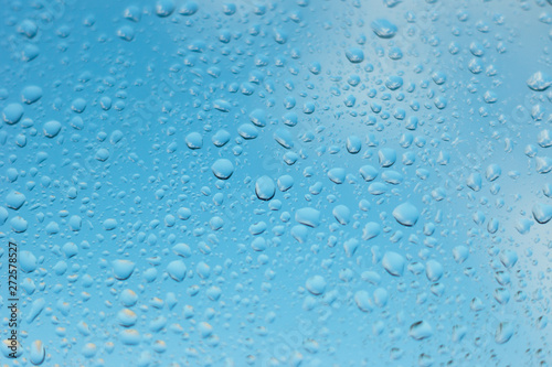 viele kleine Wassertropfen auf einer Scheibe in blau bei Regen