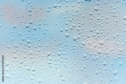 viele kleine Wassertropfen auf einer Scheibe in blau bei Regen