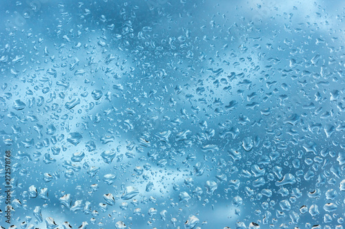 viele kleine Wassertropfen auf einer Scheibe in blau bei Regen