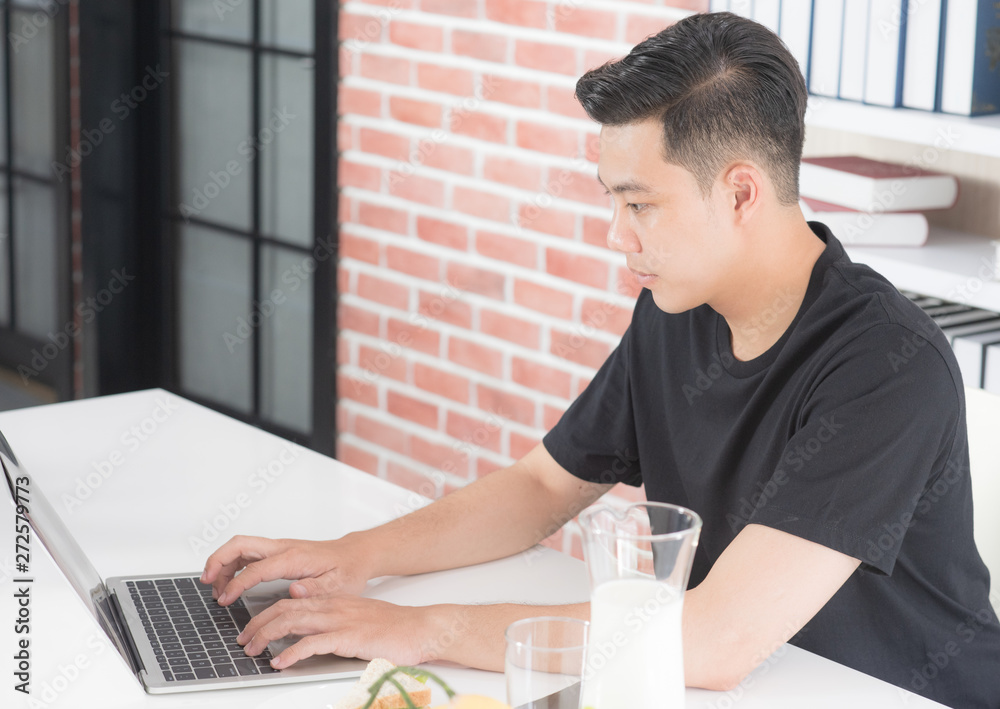 Young Asian man doing business work before eating breakfast in dinner room Young Asian man doing business work before eating breakfast in dinner room