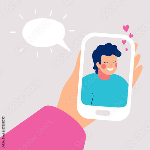 Human hand holds mobile smartphone with smiling young man on display. Speech bubble above. Vector cartoon illustration of phone conversation