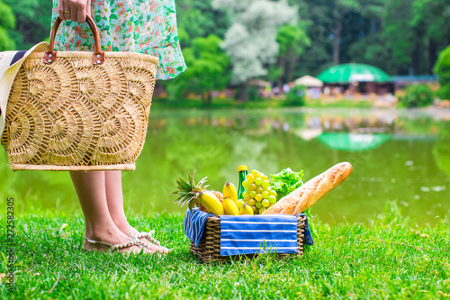 Picnic basket with fruits, bread and hat on straw bag photo