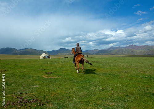 Boy Riding A Horse In The Steppe, Saralasaz Jailoo, Kyrgyzstan photo